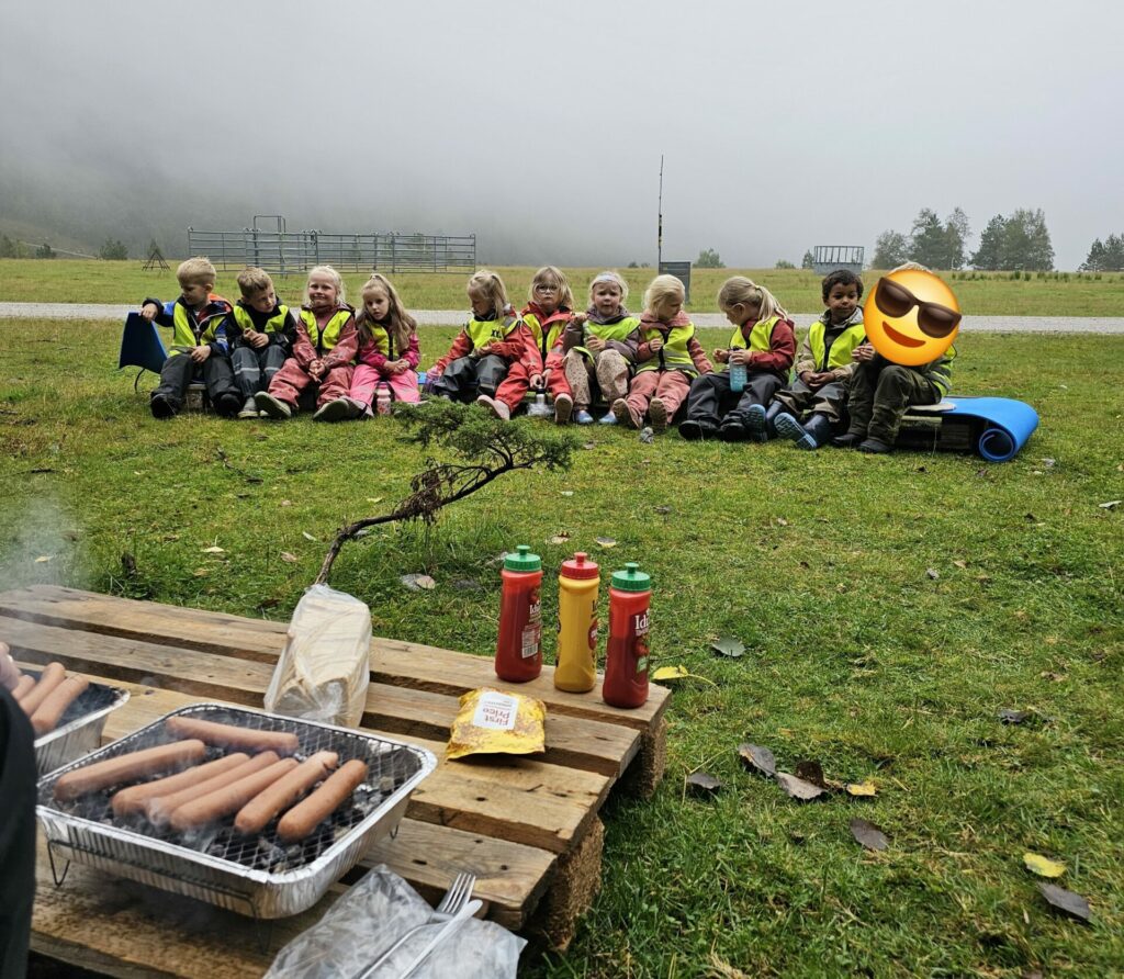 Barna fra Tonstad Barnehage sitter samlet og venter på grillmat.